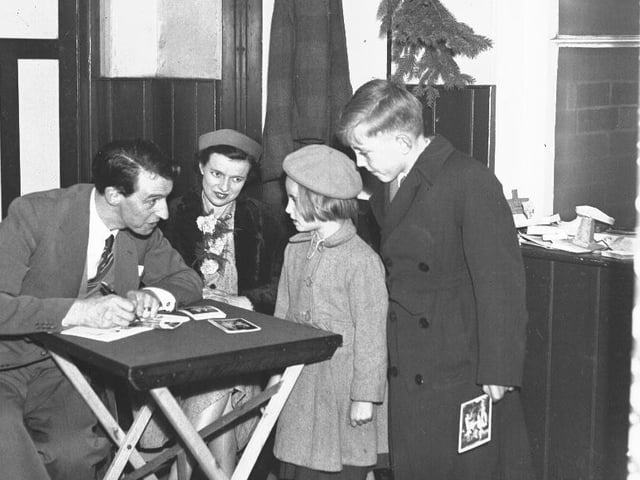 A man signing pictures autograph for children