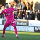 Louie Moulden fist pumps in front of the Cobblers fans after keeping his first clean sheet