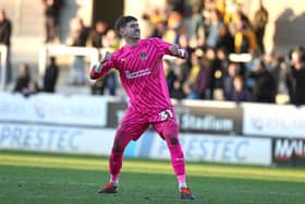 Louie Moulden fist pumps in front of the Cobblers fans after keeping his first clean sheet