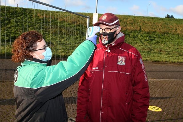 Northampton Town fans undergo a temperature check as they return to watch their team for the first game since 07.03.20 due to the coronavirus pandemic during the Sky Bet League One match between Northampton Town and Doncaster Rovers at PTS Academy Stadium on December 05, 2020.