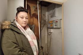 Chelsea Day stood next to the electricity box cupboard in her NPH flat which has a water leak coming from the ceiling and black mould sprouting on the walls