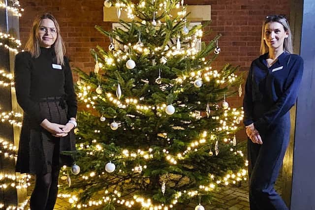 The Nordman Fir Tree all lit up with the homes Manager Larisa and Deputy Manager Diana