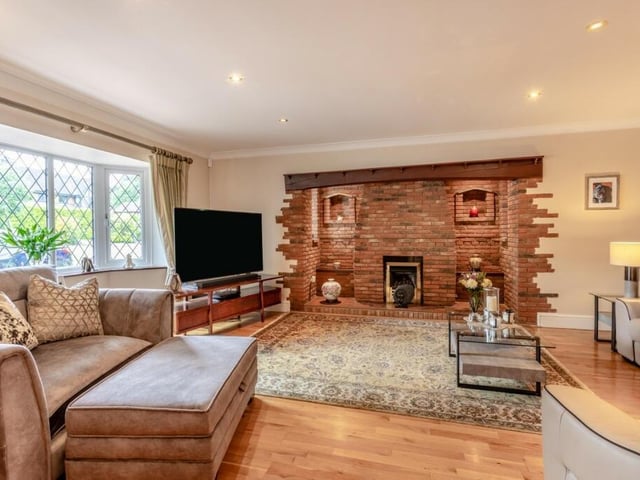 The living room features an enormous stone hearth and wooden mantle, as well as a large bay window ushering in light