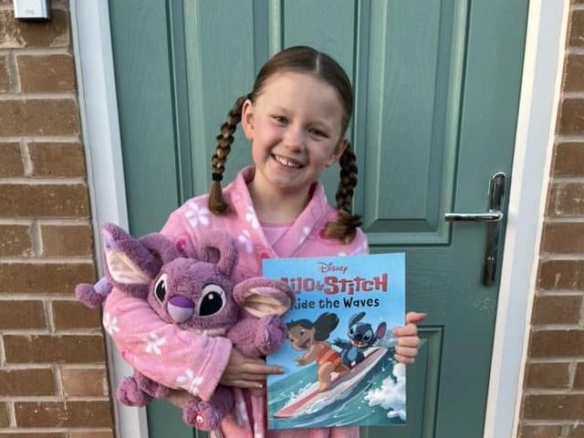 Daisy-Mae, aged 8, ready for PJ day, along with favourite teddy and book - Stitch.