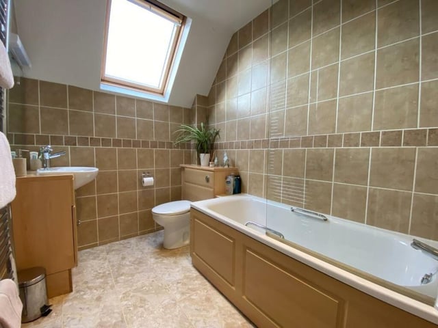 A bathroom boasts a skylight ushering in natural light throughout the day