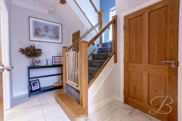 The welcoming hallway has a tiled floor and storage cupboard, and gives access to the living room and also the stairs.