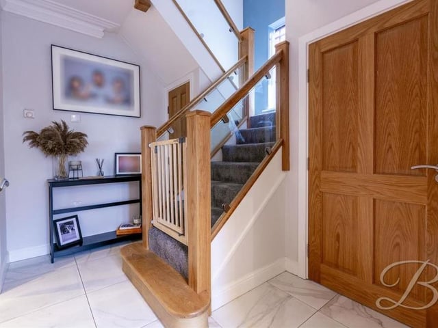 The welcoming hallway has a tiled floor and storage cupboard, and gives access to the living room and also the stairs.