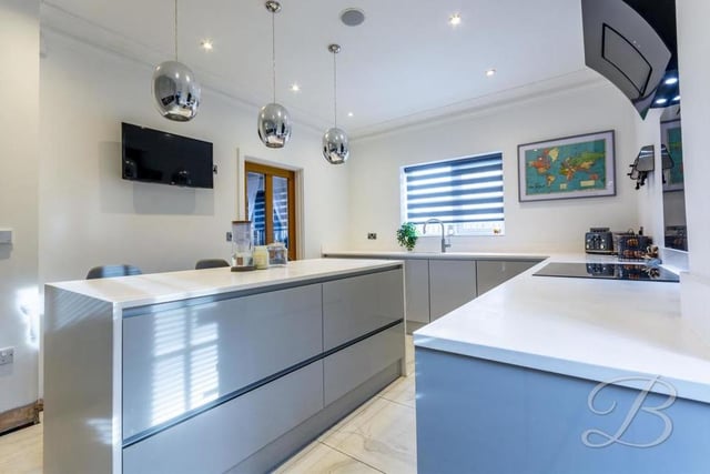 The central island in the kitchen doubles up as a breakfast bar. The sleek and stylish room also features integrated appliances, including ovens and a fridge/freezer.