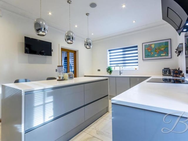 The central island in the kitchen doubles up as a breakfast bar. The sleek and stylish room also features integrated appliances, including ovens and a fridge/freezer.