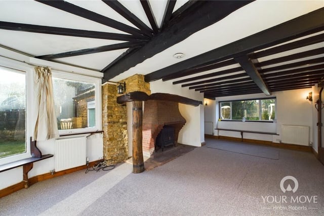 An airy living room is made all the more charming by wooden beams and a stone fireplace