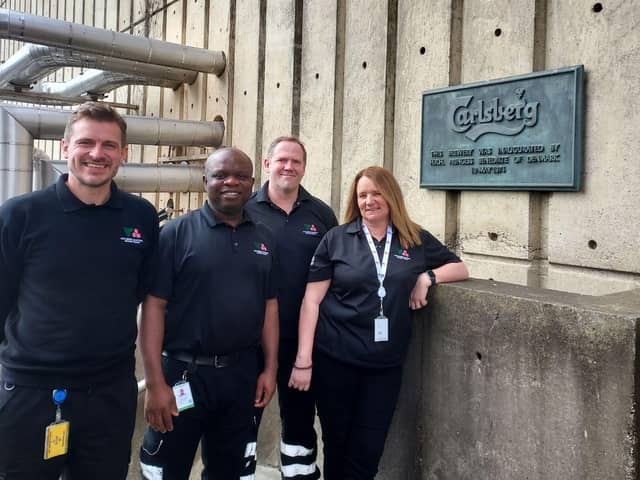 Head of quality Tom Spencer, head brewer John Njoku, head of packaging Tim van Heusden and director of brewing Emma Gilleland in front of the 1974 inauguration plaque at Carlsberg Northampton.