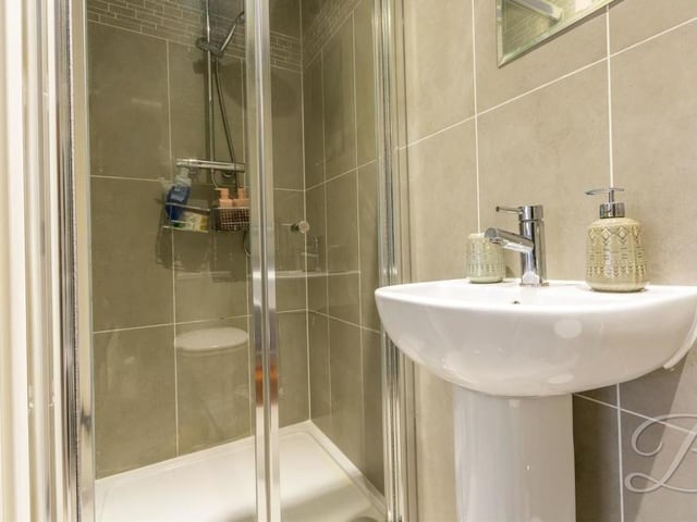 The en suite to the master bedroom includes a walk-in shower, pedestal hand wash basin, low-flush WC and chrome, heated towel-rail.