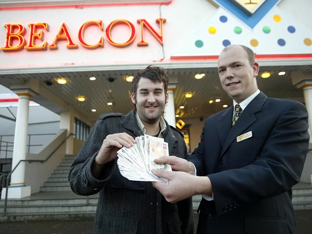 Bingo winner Thomas Carpenter receiving his money from Phil Brown, duty manager at Beacon Bingo.