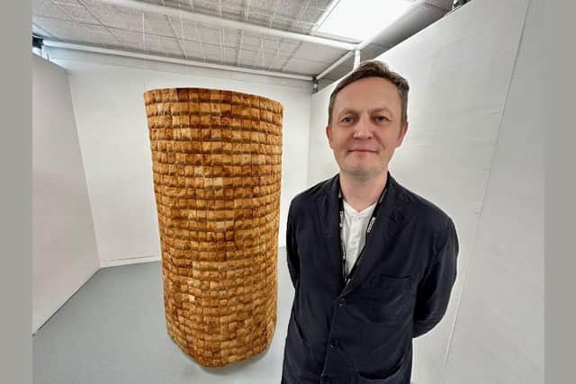 Dr Craig Staff posses with the tower of teabags created by artist Sarah Watts