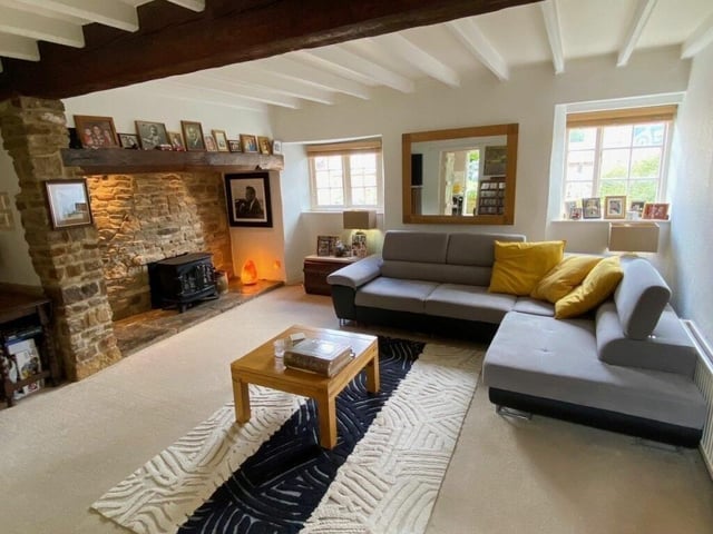 The living room comes with wooden beams and an inglenook fireplace