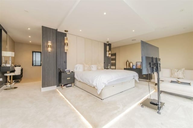 A master bedroom has enough room for its own seating area and even a mobile television stand
