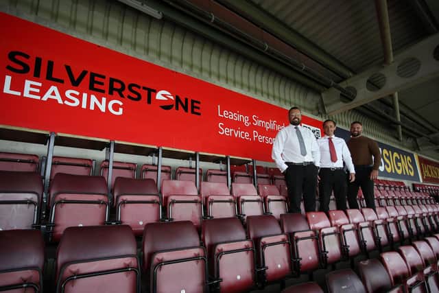 Silverstone Leasing team leader Ryan Bishop and managing director Scott Norville with NTFC commercial director James Corrigan with their new board at the ground.