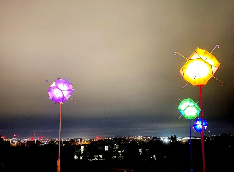 The last leg of the trail features a beautiful 'umbrella carousel' display, set against the backdrop of the twinkling lights of the city itself.