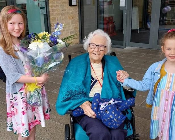 Mrs Reddy, who officially opened the new centre, receives a coronation teddy bear and flowers from nine year old Ariana (left) and five year old Arabella.