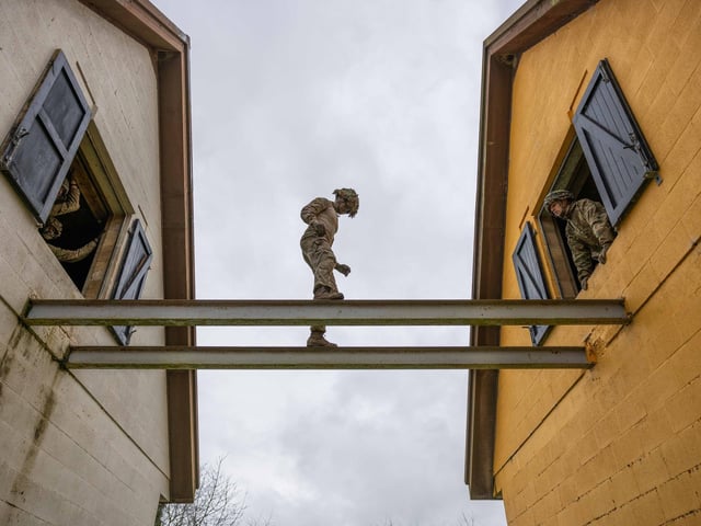 A soldier from 2nd Battalion The Royal Anglian Regiment balances across steel girders from house to house during his Confidence Course run in Copehill Down