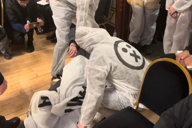 A campaigner stood up in a coughing fit before collapsing to the floor to stage a death. Other 1000 voices members entered the Guildhall to carry him out. Credit: 1000 voices