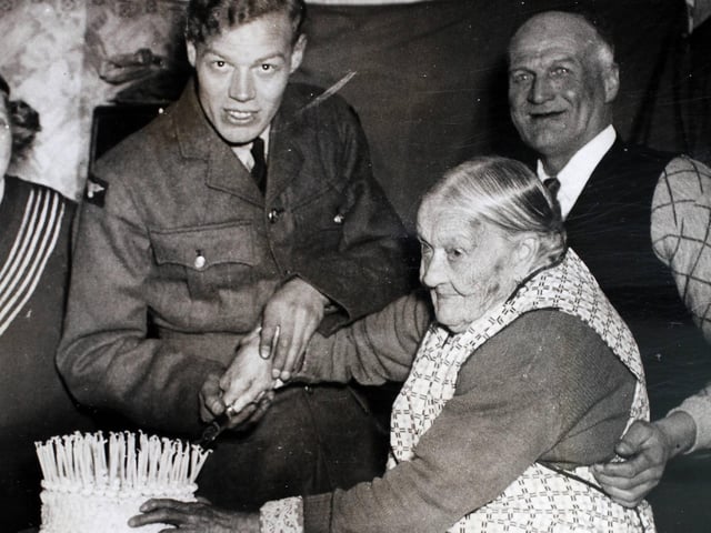 December 1939. Aircraftsman RF Adcock assists his grandmother, Mrs Sarah Adcock of Northampton, in cutting her 106th birthday cake decorated with 106 candles at her party. On the right of the picture can be seen her youngest son, who is 57 years of age and whom she still calls 'baby'. Mrs Adcock will be remembered as being the oldest woman to fly in an aeroplane not long ago. She can recall three major wars. (Photo by Fox Photos/Hulton Archive/Getty Images)