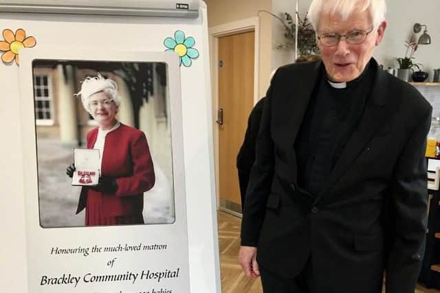 Rev Canon Peter Woodward pictured in front of poster of Delia Frost with her MBE. Canon Woodward delivered the moving eulogy at Delia's funeral.