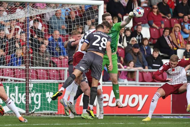 Lee Burge punches the ball clear under pressure from Newport's Mickey Demetriou (Picture: Pete Norton)