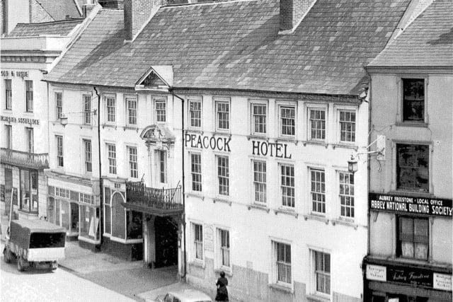 The George Hotel may have been the more famous nationally, but the Peacock Hotel is by far and away the most famous and well regarded within Northampton. Although it closed down over 60 years ago, the sense of outrage at its demolition has echoed down the years, through personal accounts, through the many books of Northampton history (no book worth its salt went without a picture of the Peacock) and now through the power of the internet with its vibrant sites dedicated to the past and present of the town.
Although it is assumed that the Peacock first appeared not long after the Market Square was first created in 1235, probability is not proof and we knew little of its history before the 1675 Fire until new documents and deed were discovered in the 1930’s and at last we could start joining the dots. The Peacock closed its doors on the 26th May 1957 and planning permission for a new shopping arcade was refused as the listed building wasn’t part of the development plans. The façade, just like that of the nearby Emporium would form a wonderful backdrop to the 21stCentury Market Square but as we know, it wasn’t to be. The building was left open to the elements until it was beyond repair, permission for its demolition was given and it was pulled down in 1960.