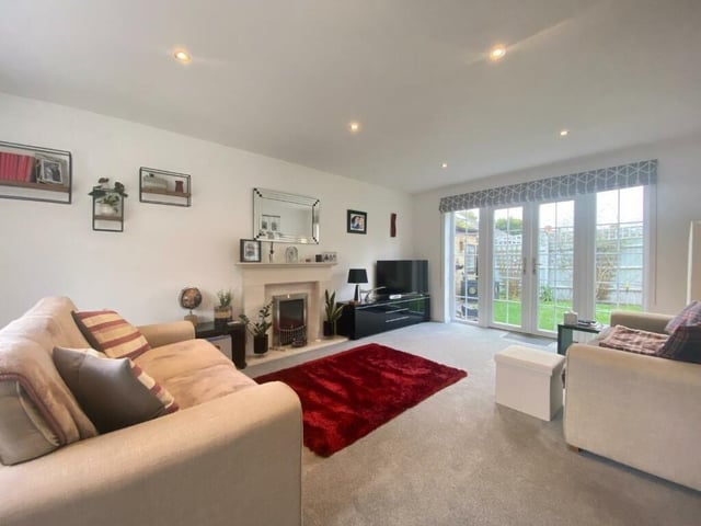 A plush living room offers heaps of space for family life, with French doors leading to the garden