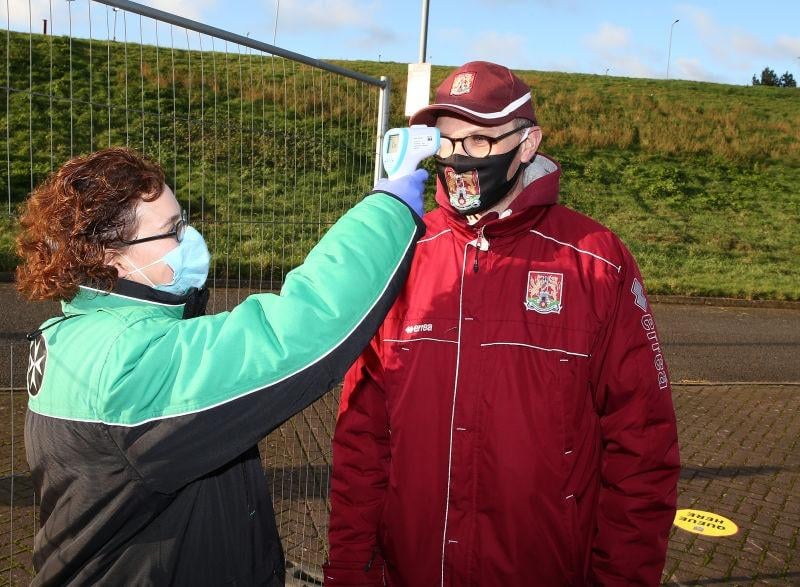 Northampton Town fans undergo a temperature check as they return to watch their team for the first game since 07.03.20 due to the coronavirus pandemic during the Sky Bet League One match between Northampton Town and Doncaster Rovers at PTS Academy Stadium on December 05, 2020.