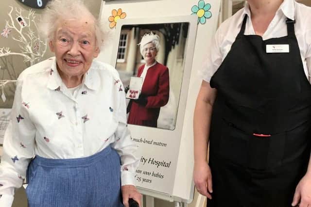 Brackley Care Home resident Marian Frost pictured with Nicky Andrews who was delivered by Delia Frost in 1971. They are pictured in front of a poster of Delia Frost with her MBE