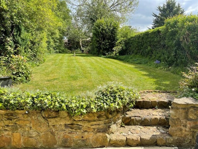 Stone steps lead up to the charming garden, surrounded by trees and hedges for privacy