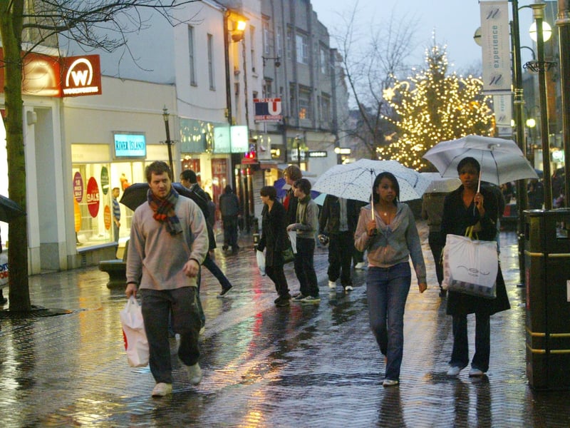 2006 - Abington Street shoppers out in the rain with a few colourful umbrellas. Eve of New Year's Eve