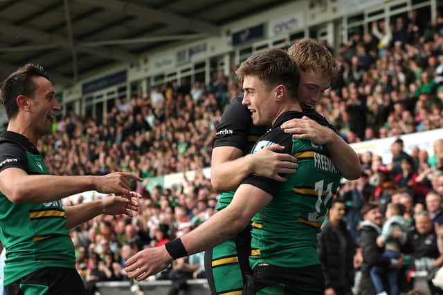 Tommy Freeman of Northampton Saints celebrates with team mates Alex Mitchell (L) and Fin Smith after scoring their third try during the Gallagher Premiership Rugby match between Northampton Saints and Saracens at Franklin's Gardens on April 15, 2023 (Photo by David Rogers/Getty Images)