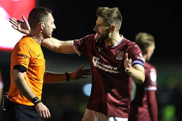 Jon Guthrie of Northampton Town makes a point to referee Simon Mather during the Sky Bet League One match between Northampton Town FC and Peterborough United FC at Sixfields on December 09, 2024 in Northampton, England. (Photo by Pete Norton/Getty Images)