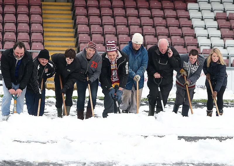 Fans clear snow from the pitch in an attempt to allow the npower League Two match between Northampton Town and Burton Albion to go ahead at Sixfields Stadium on January 19, 2013.