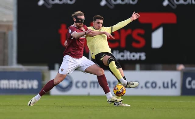 Tom Eaves and former Cobblers defender Lloyd Jones challenge for the ball.