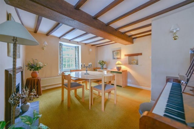 A front-facing dining room has traditional wooden beams and an ornate fireplace
