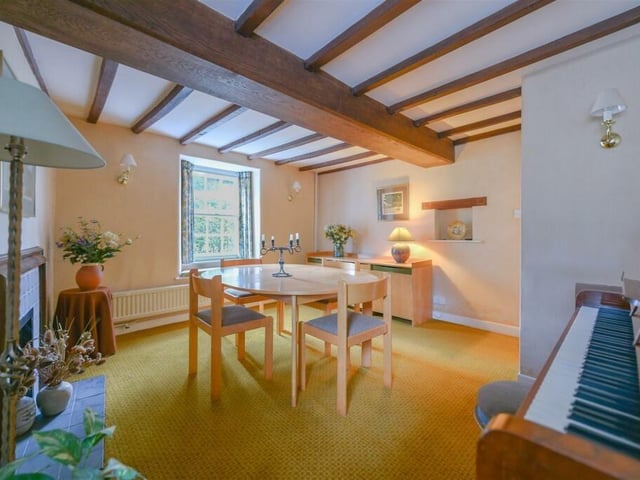 A front-facing dining room has traditional wooden beams and an ornate fireplace