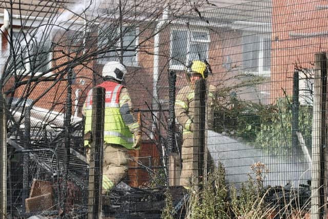 Firefighters damp down the destroyed gardens
