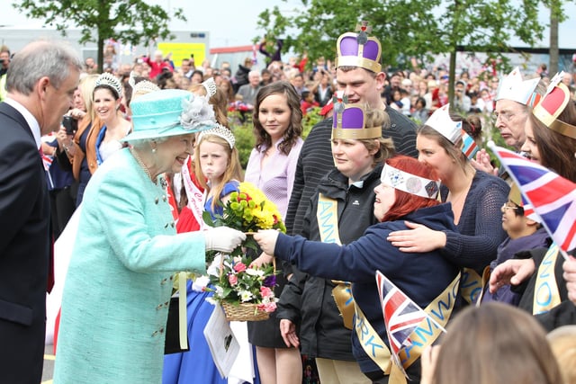 Her Majesty Elizabeth Queen II accepts a basket of flowers from a well-wisher in the crowd, June 2012
