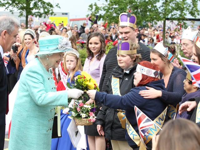 Her Majesty Elizabeth Queen II accepts a basket of flowers from a well-wisher in the crowd, June 2012
