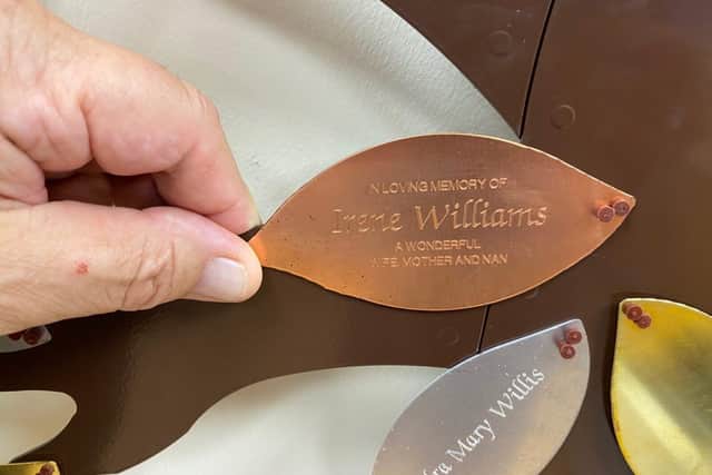 A metal leaf inscribed with a name and message.