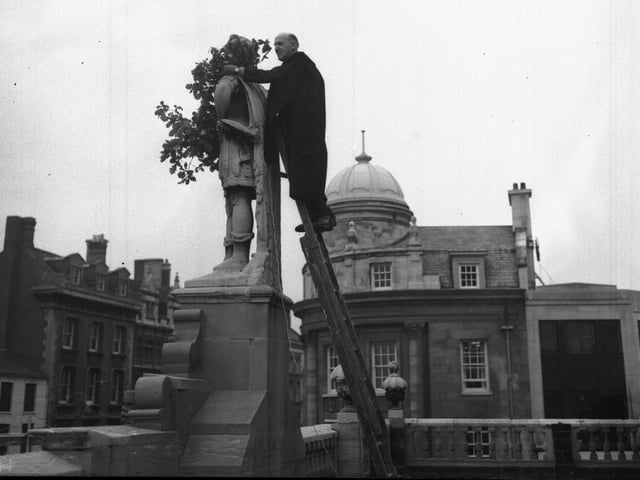 Putting a wreath around King Charles's statue on top of All Saints Church portico, Northampton