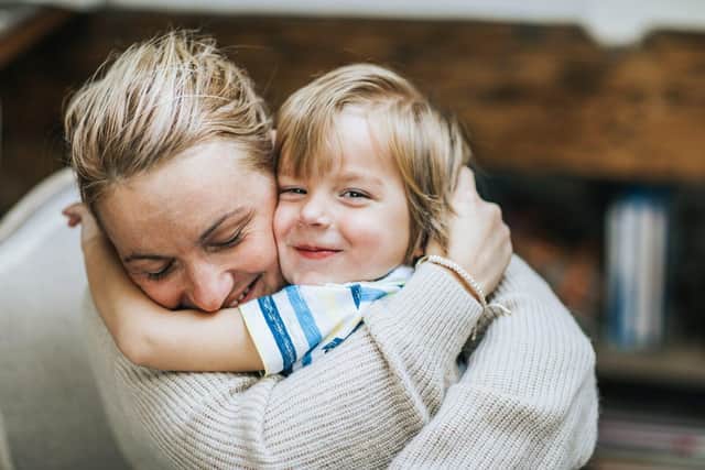 A women and young boy hugging while smiling at the Camera