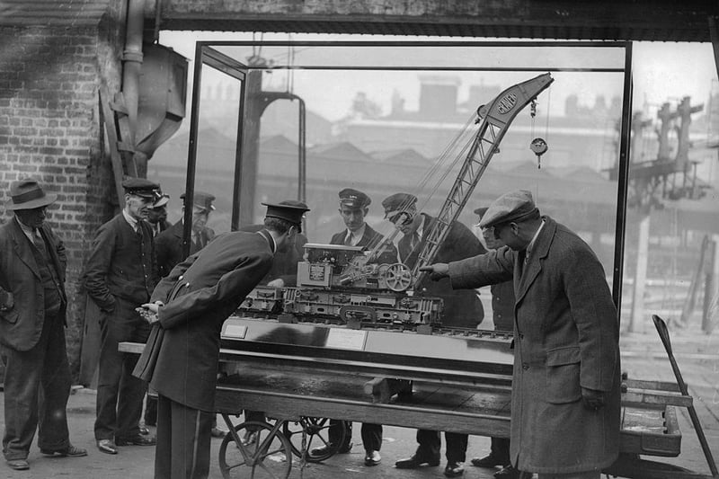 Train model maker A Mr Ward of Northampton is pictured explaining his model LMS Rugby steam crane to porters at Euston. On display in the Great Mall, Euston station in London. The model took him 18 months to make.