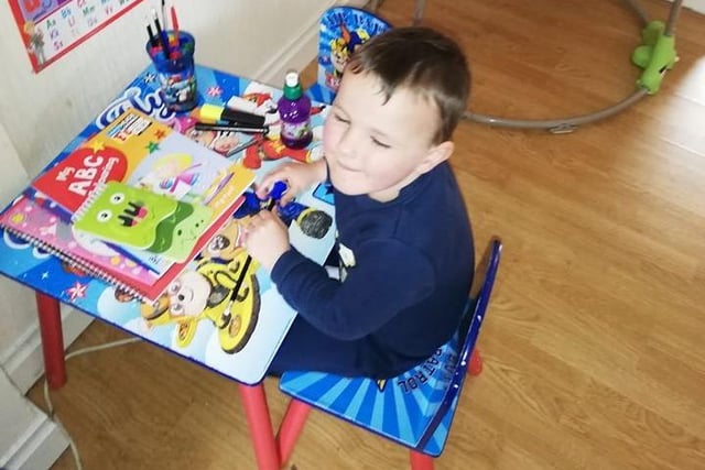 George, five, is surrounded by pens and books.
