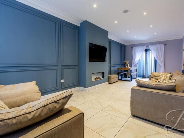 Our first glance at the luxurious living room, which is a vast space. Feel at home with the feature fireplace and beautiful, panelled feature wall as you relax to your heart's content. Patio doors lead out to the back garden.