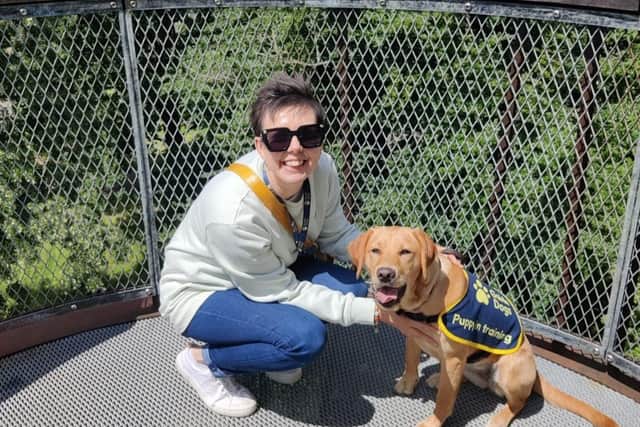 Volunteer Puppy Raiser Claire Reedman kneeling next to guide dog puppy Sophie.